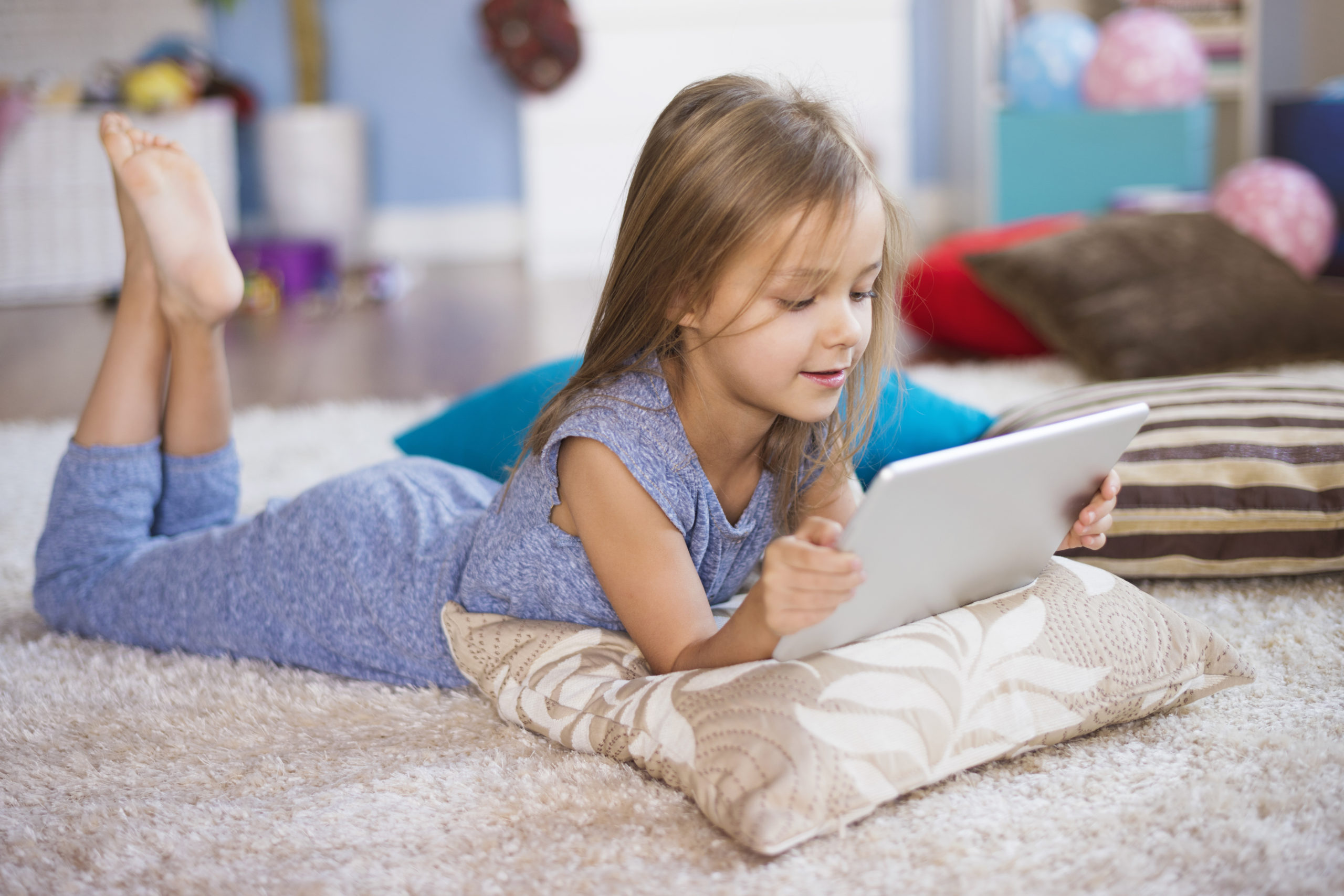 Little girl with digital tablet on the rug
