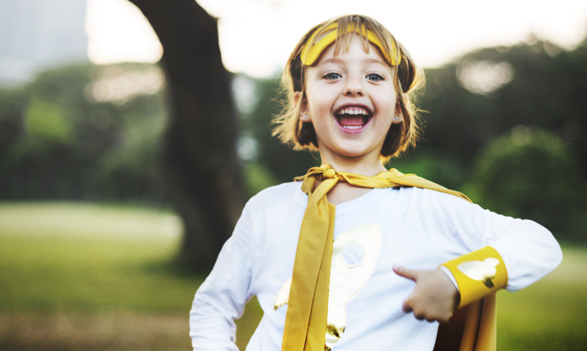 Young caucasian girl smiling  wearing superhero costume in the park